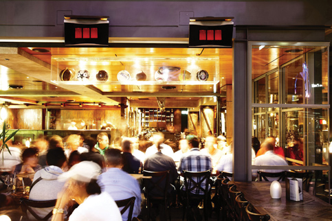 Busy restaurant with customers dining and socialising in a warm indoor setting.