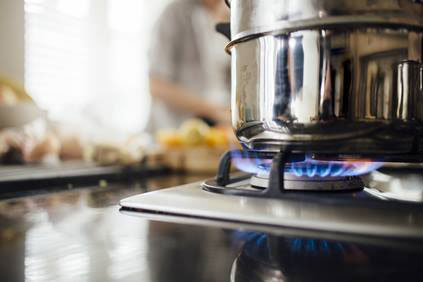 Stainless steel pot on a gas stove with flames underneath, representing natural gas cooking.