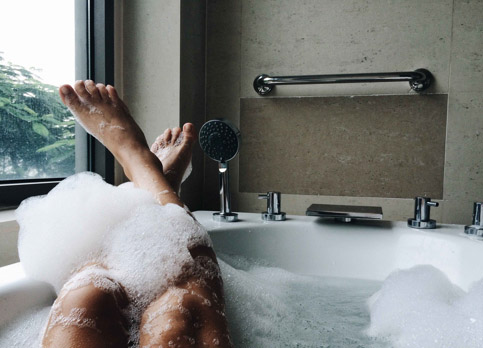 Person relaxing in a bathtub filled with warm water, heated by a gas system.