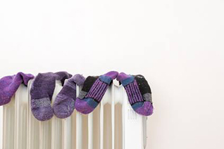 Purple socks drying on top of the gas heater at home. 