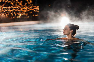 A person diving into a luxurious outdoor heated pool at night.