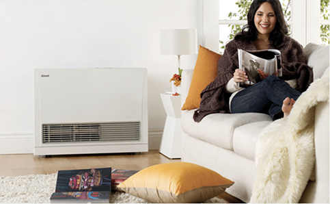 Woman relaxing on a couch with a gas heater warming the room.