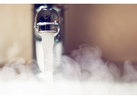 Bathtub tap releasing hot water, with visible steam rising