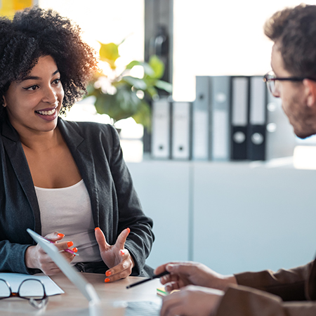 Professional woman in conversation with a colleague in an office setting.