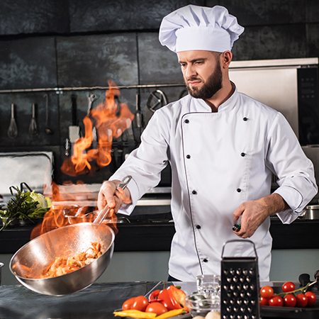 Chef cooking with a gas flame for precise temperature control.