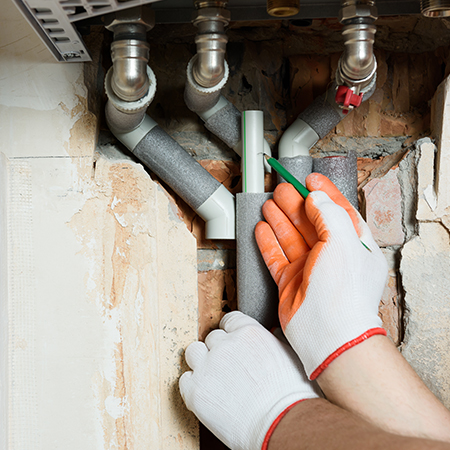 Plumber working on gas pipes, symbolising maintenance and installation of gas infrastructure.