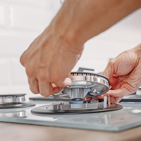 A person installing a gas stove for household cooking